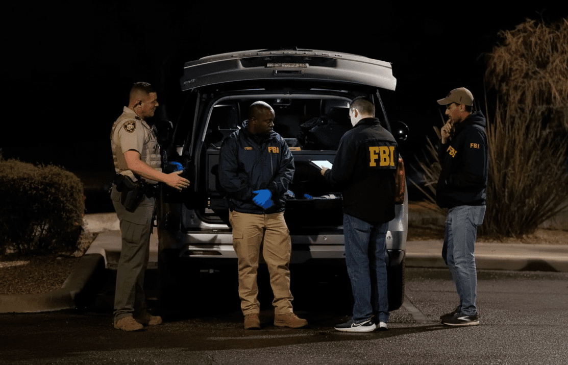 SWAT team members in tactical gear surround a suburban house while police vehicles line the street.