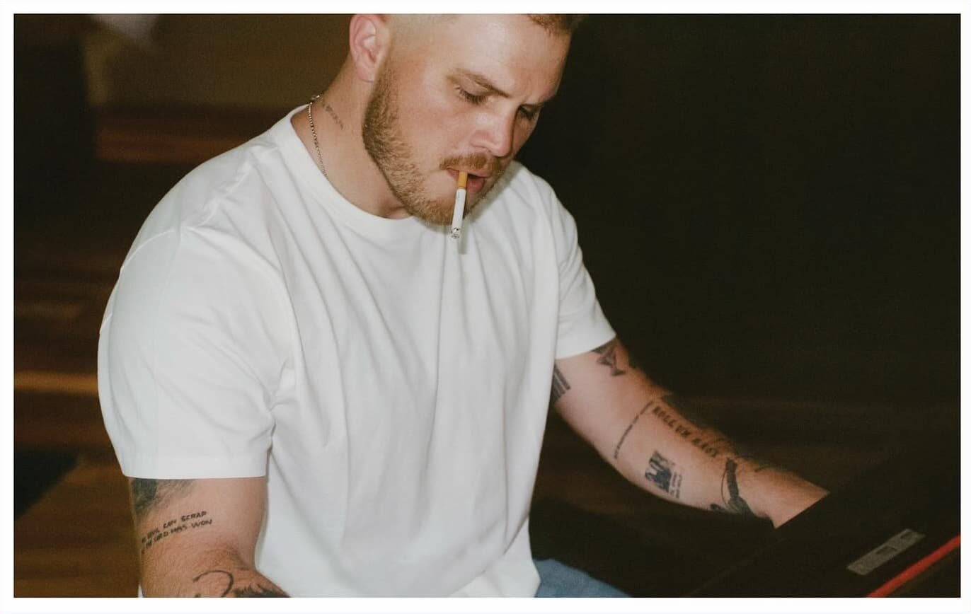 Jason Aldean and Luke Bryan on stage at a concert, both wearing denim jackets and jeans, engaging with the crowd.