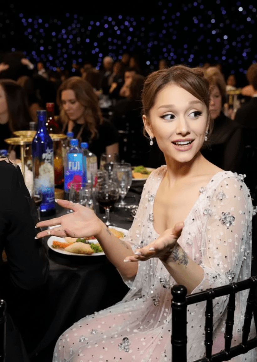 Leighton Meester and Ariana Grande smiling and chatting at the Critics Choice Awards, both wearing elegant evening gowns.