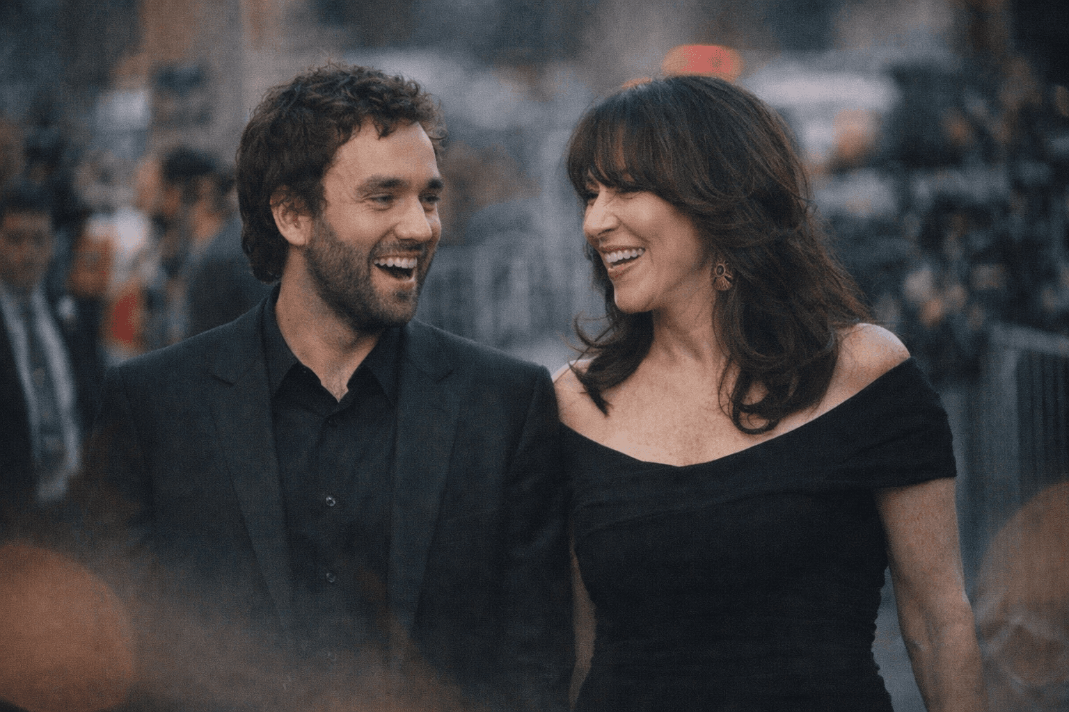 Katey Sagal smiling warmly, wearing a floral dress, stands next to her son Jackson White in a casual shirt at an outdoor even
