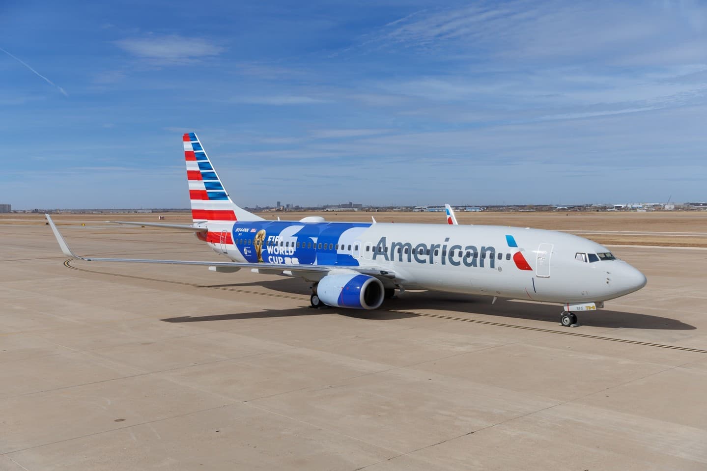 Jim Breuer sitting in an airport lounge wearing a casual black t-shirt and jeans, looking frustrated while checking his phone