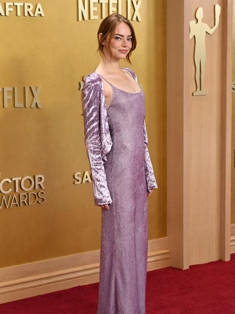 Emma Stone wearing a bold, asymmetrical dress with bright colors and unique patterns on the red carpet at the SAG Awards.